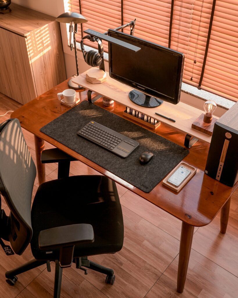 Minimal wooden desk setup with monitor, keyboard, and office chair